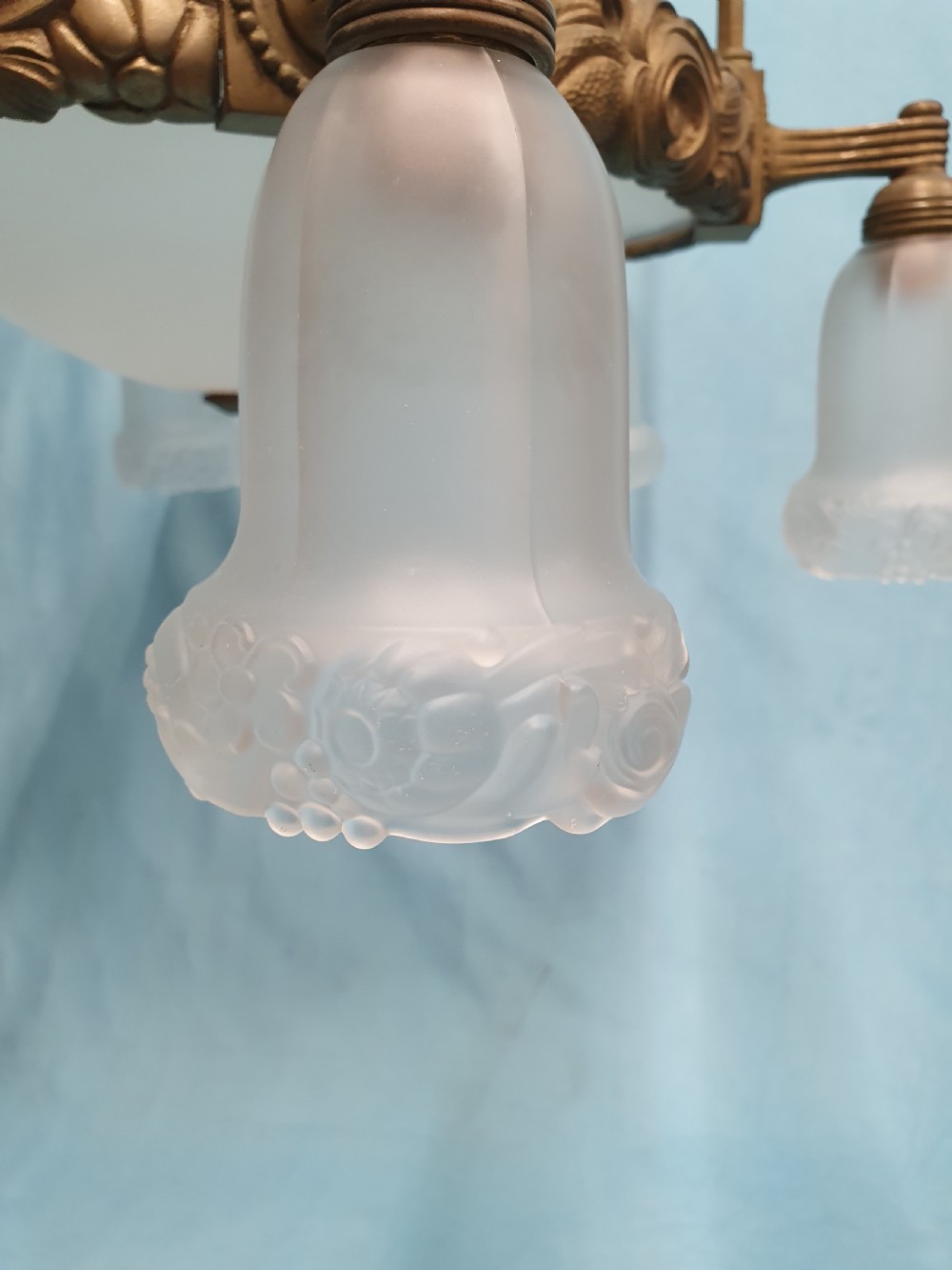 A pair of early 20th-century brass pendant lights featuring tall angular cage frames supporting ornate floral band bases with multiple suspended frosted glass shades. View V