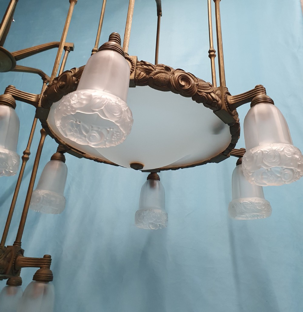 A pair of early 20th-century brass pendant lights featuring tall angular cage frames supporting ornate floral band bases with multiple suspended frosted glass shades. View VI