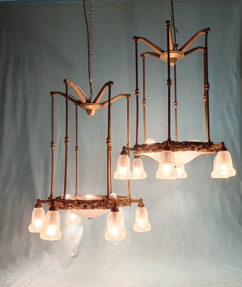 A pair of early 20th-century brass pendant lights featuring tall angular cage frames supporting ornate floral band bases with multiple suspended frosted glass shades. View VII