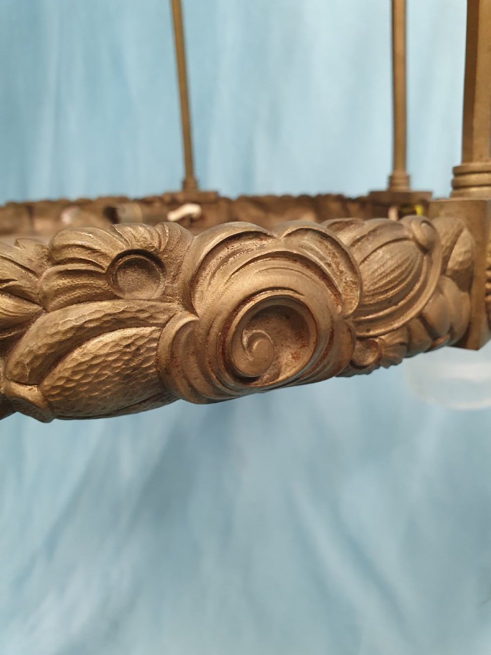 A pair of early 20th-century brass pendant lights featuring tall angular cage frames supporting ornate floral band bases with multiple suspended frosted glass shades. View X