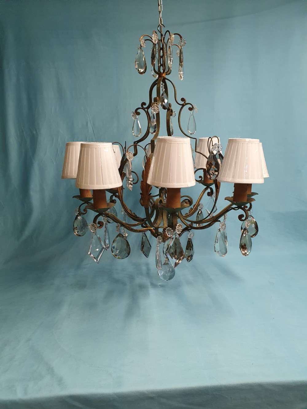 An early twentieth-century French green steel six-light chandelier adorned with faceted crystal glass drops and pleated white fabric shades.