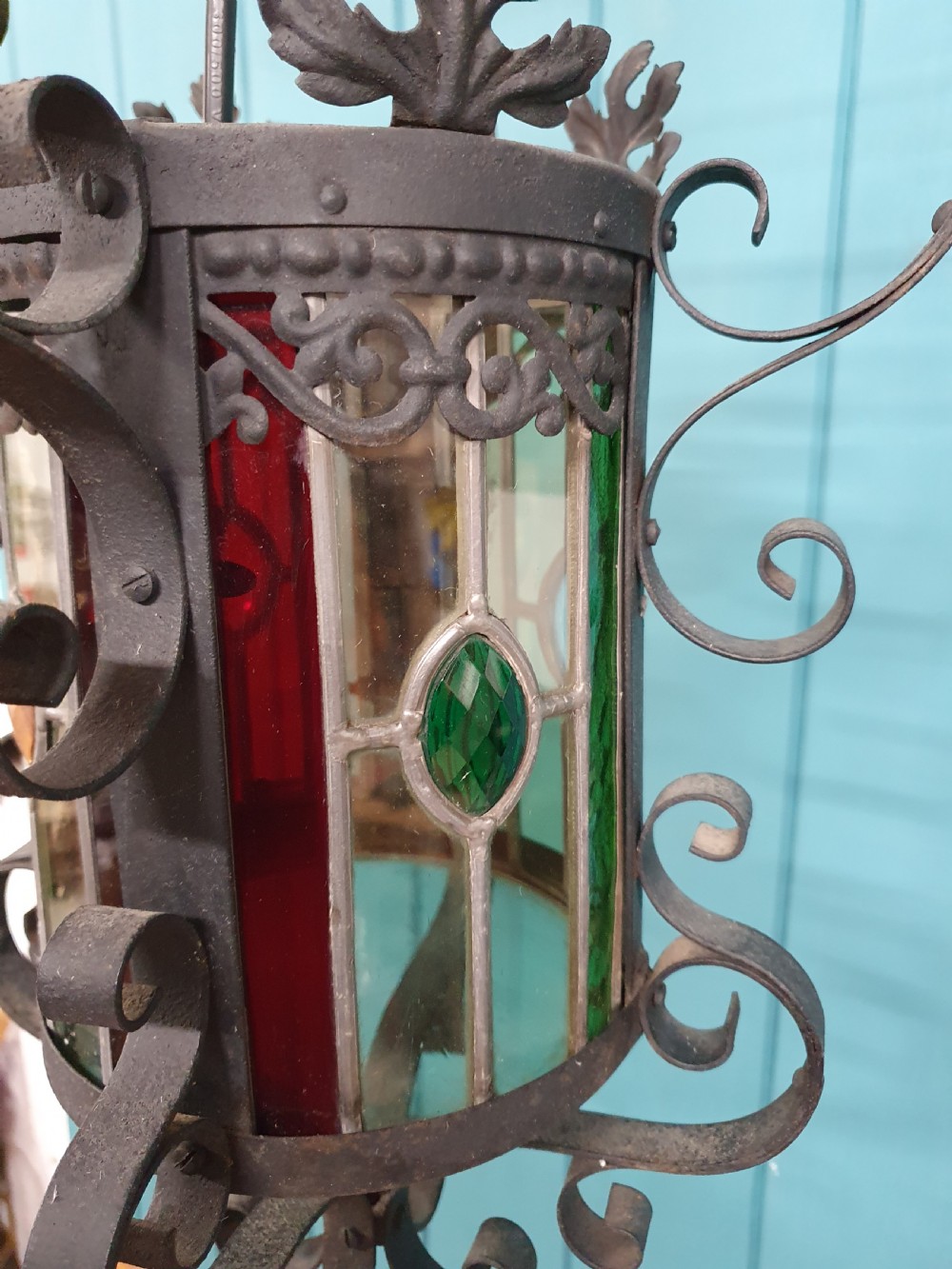 An early 20th-century hanging French porch lantern crafted from dark wrought iron scrollwork with leaded glass panels. View III