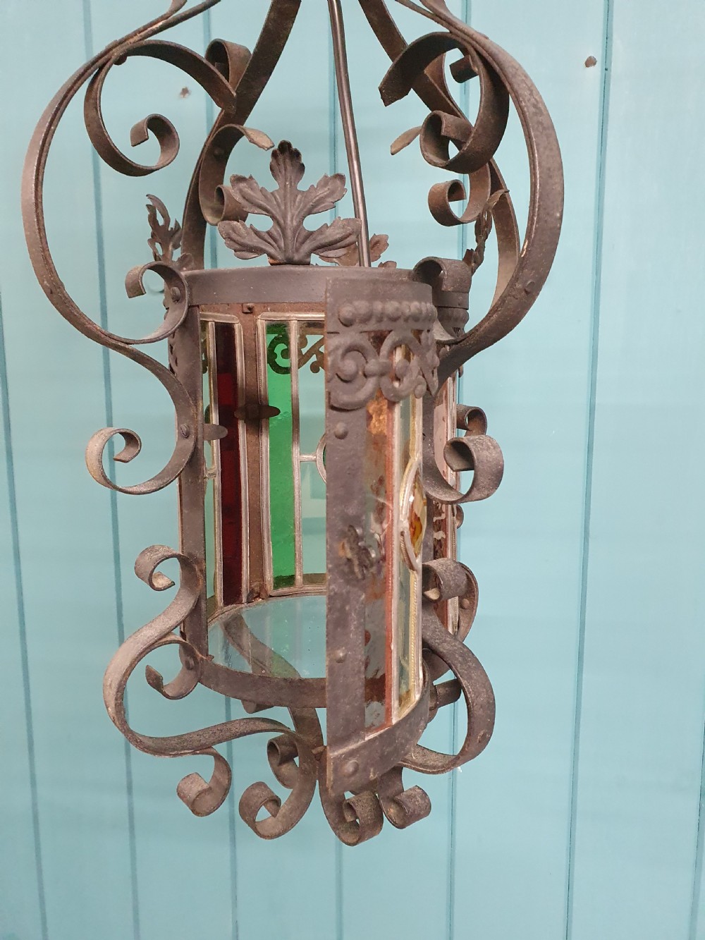 An early 20th-century hanging French porch lantern crafted from dark wrought iron scrollwork with leaded glass panels. View V