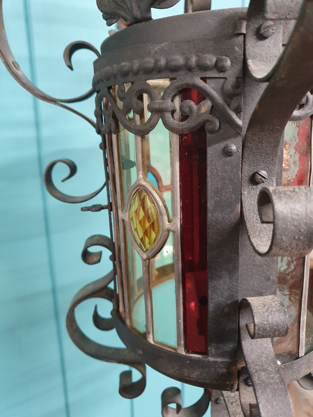 An early 20th-century hanging French porch lantern crafted from dark wrought iron scrollwork with leaded glass panels. View VIII