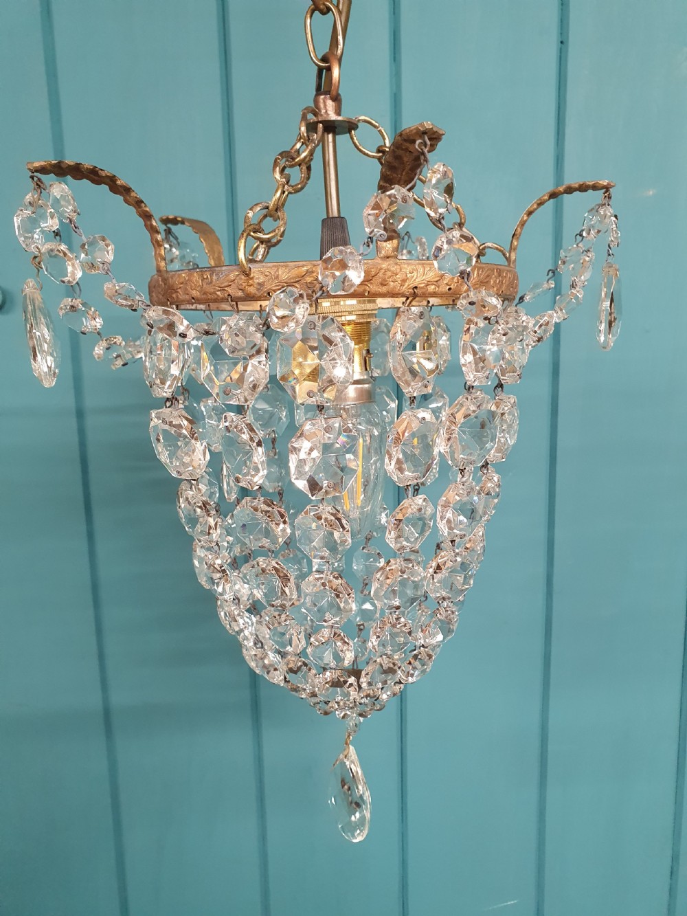 A small early 20th-century ceiling pendant featuring a brass frame hung with faceted clear glass crystal beads formed into a tapered basket shape. View II