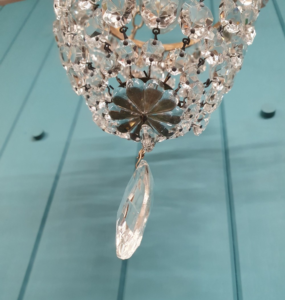 A small early 20th-century ceiling pendant featuring a brass frame hung with faceted clear glass crystal beads formed into a tapered basket shape. View VI