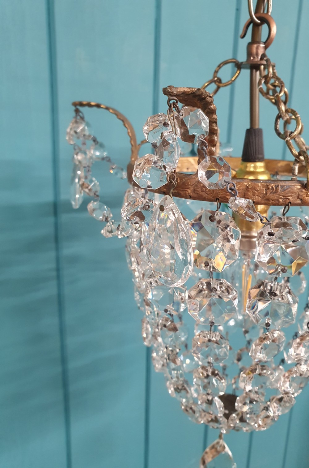 A small early 20th-century ceiling pendant featuring a brass frame hung with faceted clear glass crystal beads formed into a tapered basket shape. View VII