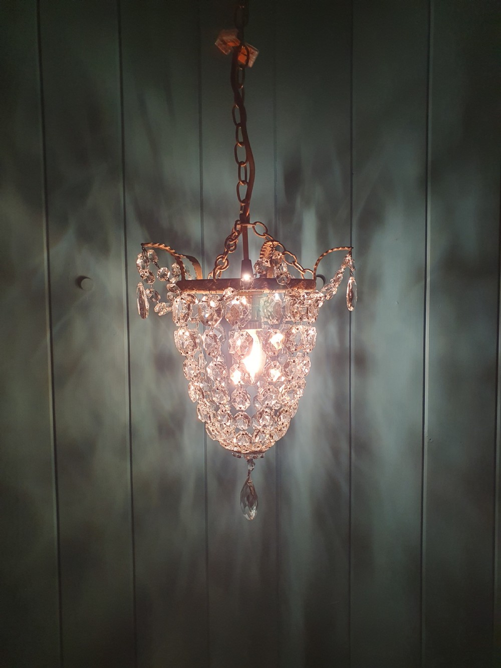 A small early 20th-century ceiling pendant featuring a brass frame hung with faceted clear glass crystal beads formed into a tapered basket shape. View VIII