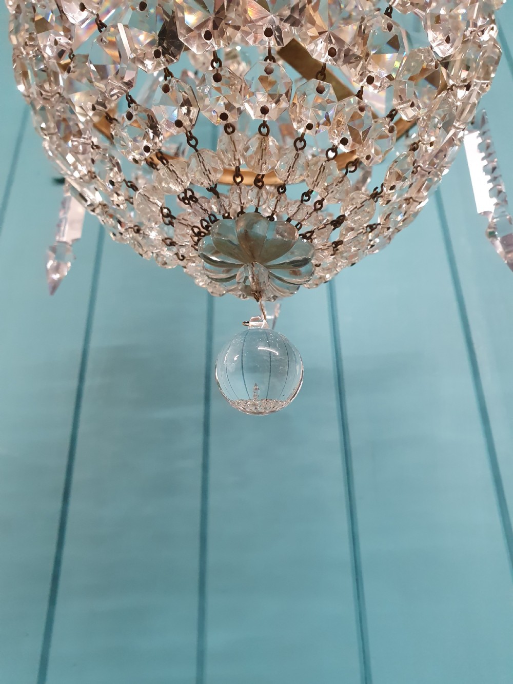 An early 20th-century swag chandelier with tiered glass crystal prisms and a gilt brass frame hanging from a chain. View III