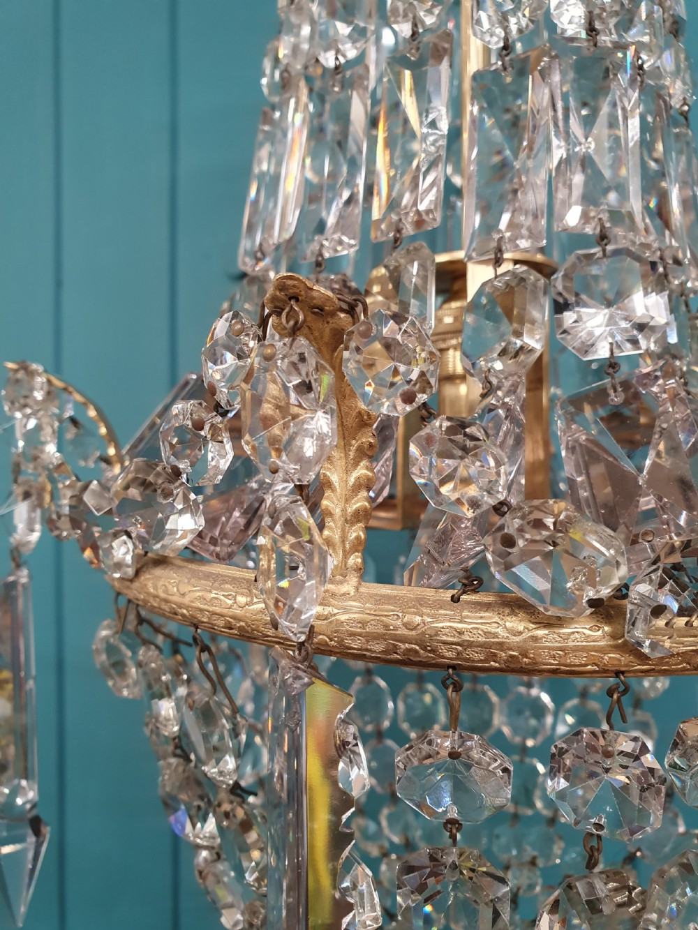 An early 20th-century swag chandelier with tiered glass crystal prisms and a gilt brass frame hanging from a chain. View VIII