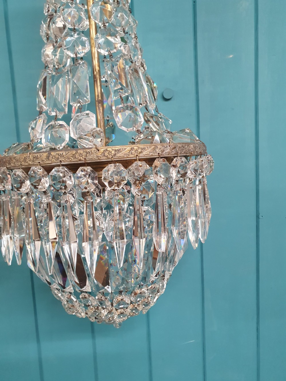 An early 20th-century crystal bag chandelier featuring cascading glass droplets suspended from a decorative brass gallery ring and chain. View V