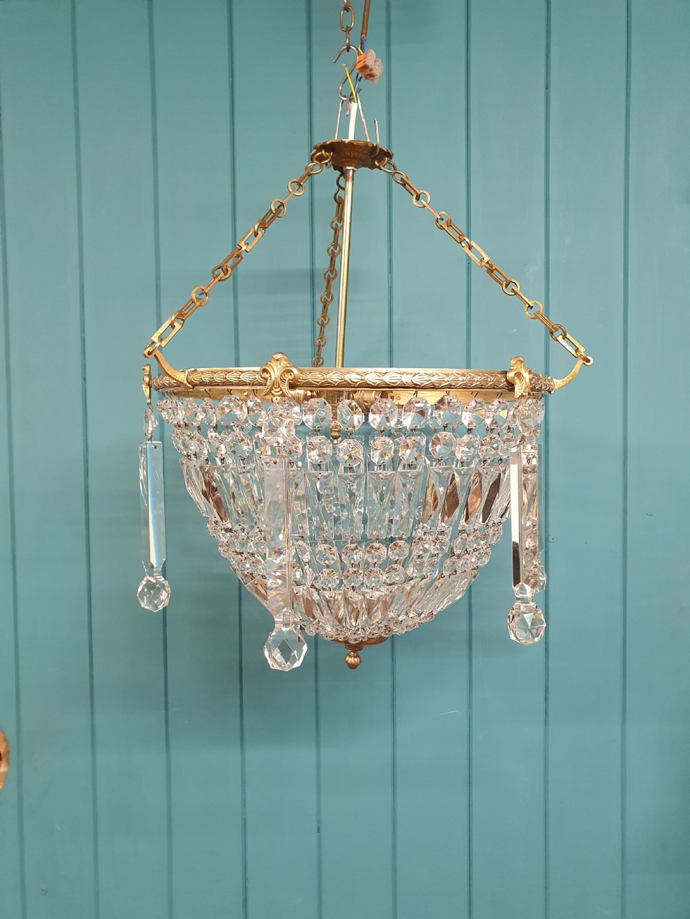 An early twentieth-century brass and cut glass bag basket chandelier with long rectangular prisms and hanging faceted glass drops.