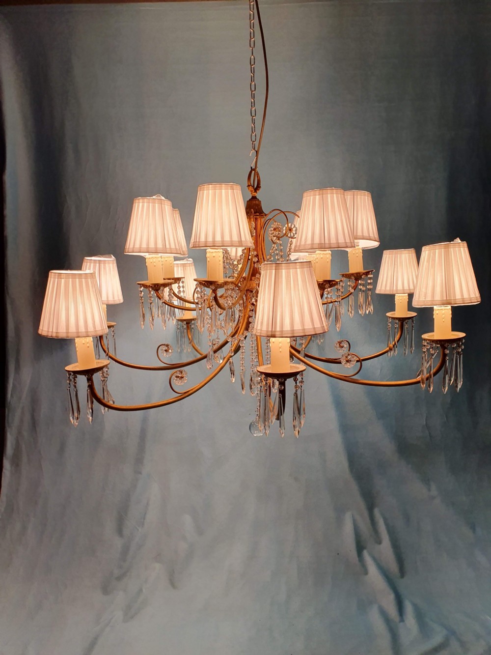 A pair of early 20th-century brass two-tier chandeliers decorated with cut glass crystal prisms, bead garlands, and candle sleeves. View X
