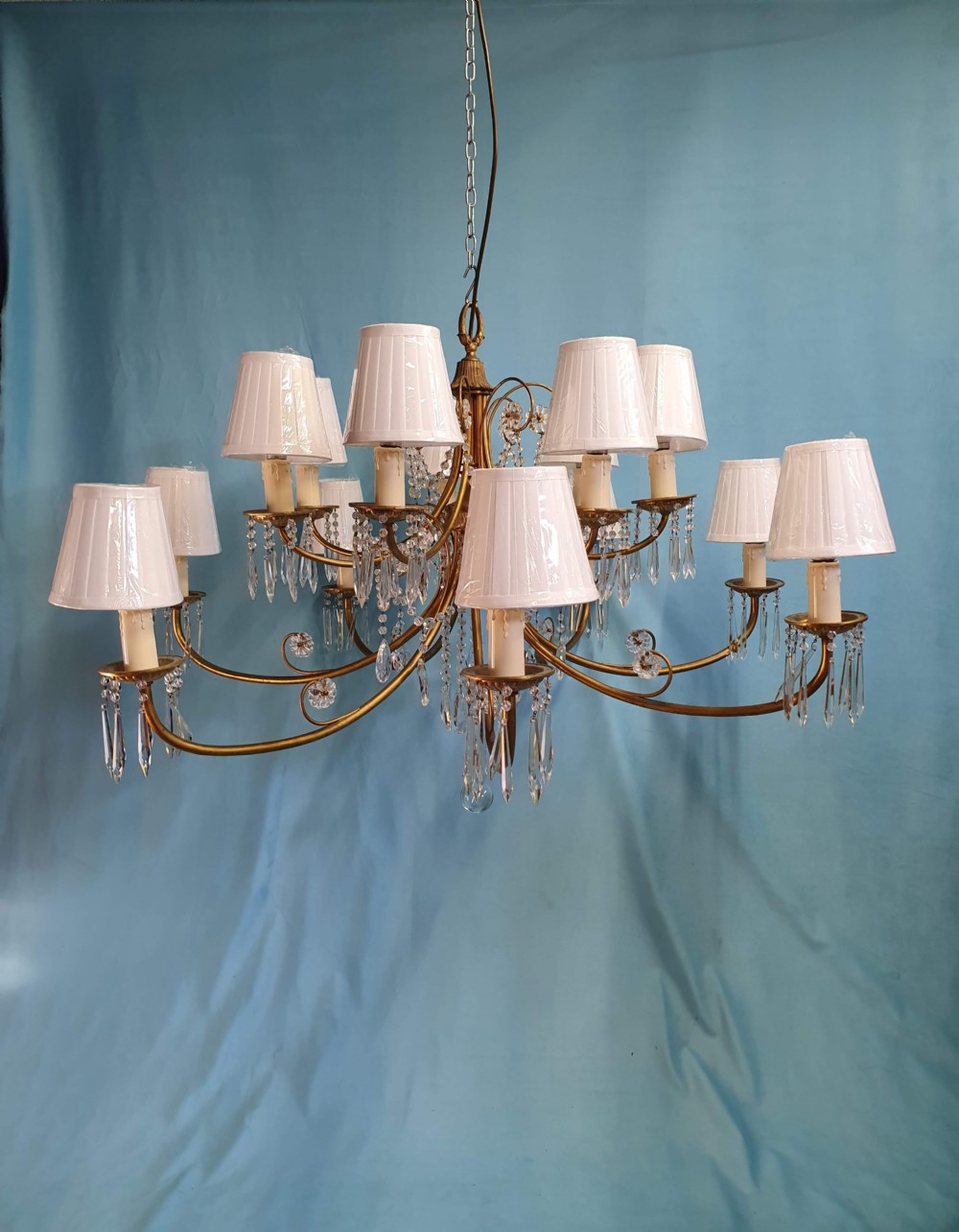 A pair of early 20th-century brass two-tier chandeliers decorated with cut glass crystal prisms, bead garlands, and candle sleeves. View XI