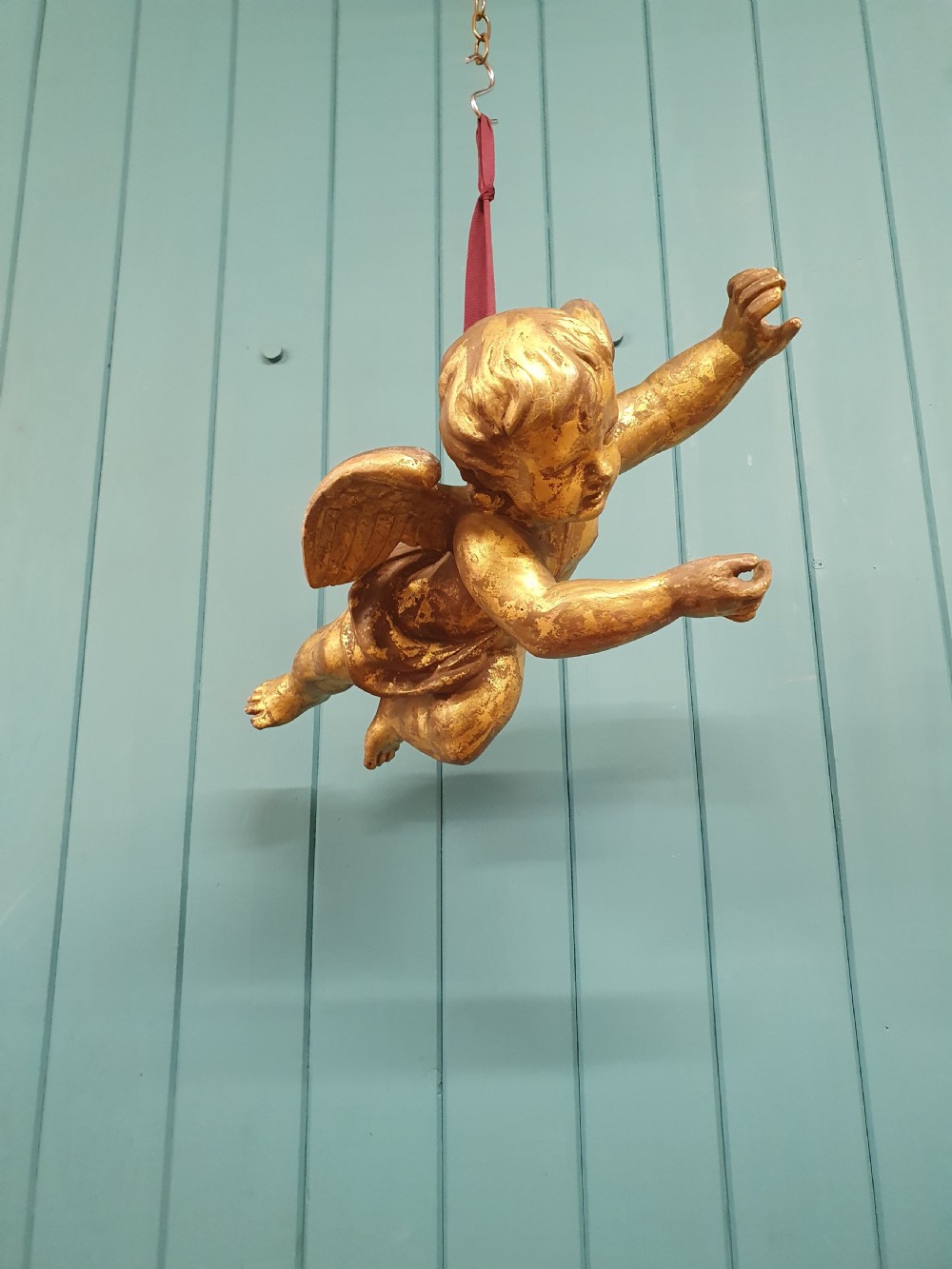 A late 19th-century hand-carved wooden cherub figure with feathered wings and extended limbs, finished in gold leaf gilding. View II