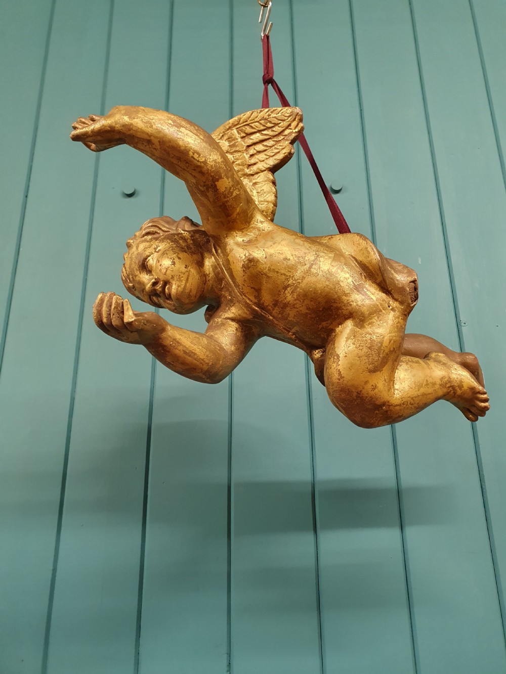 A late 19th-century hand-carved wooden cherub figure with feathered wings and extended limbs, finished in gold leaf gilding. View III