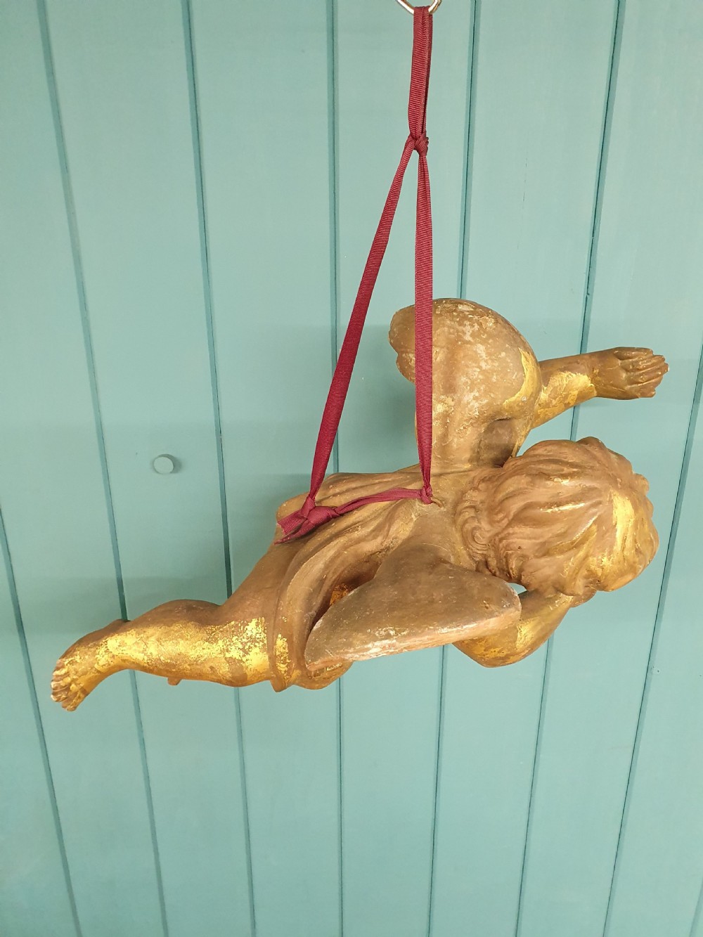 A late 19th-century hand-carved wooden cherub figure with feathered wings and extended limbs, finished in gold leaf gilding. View V