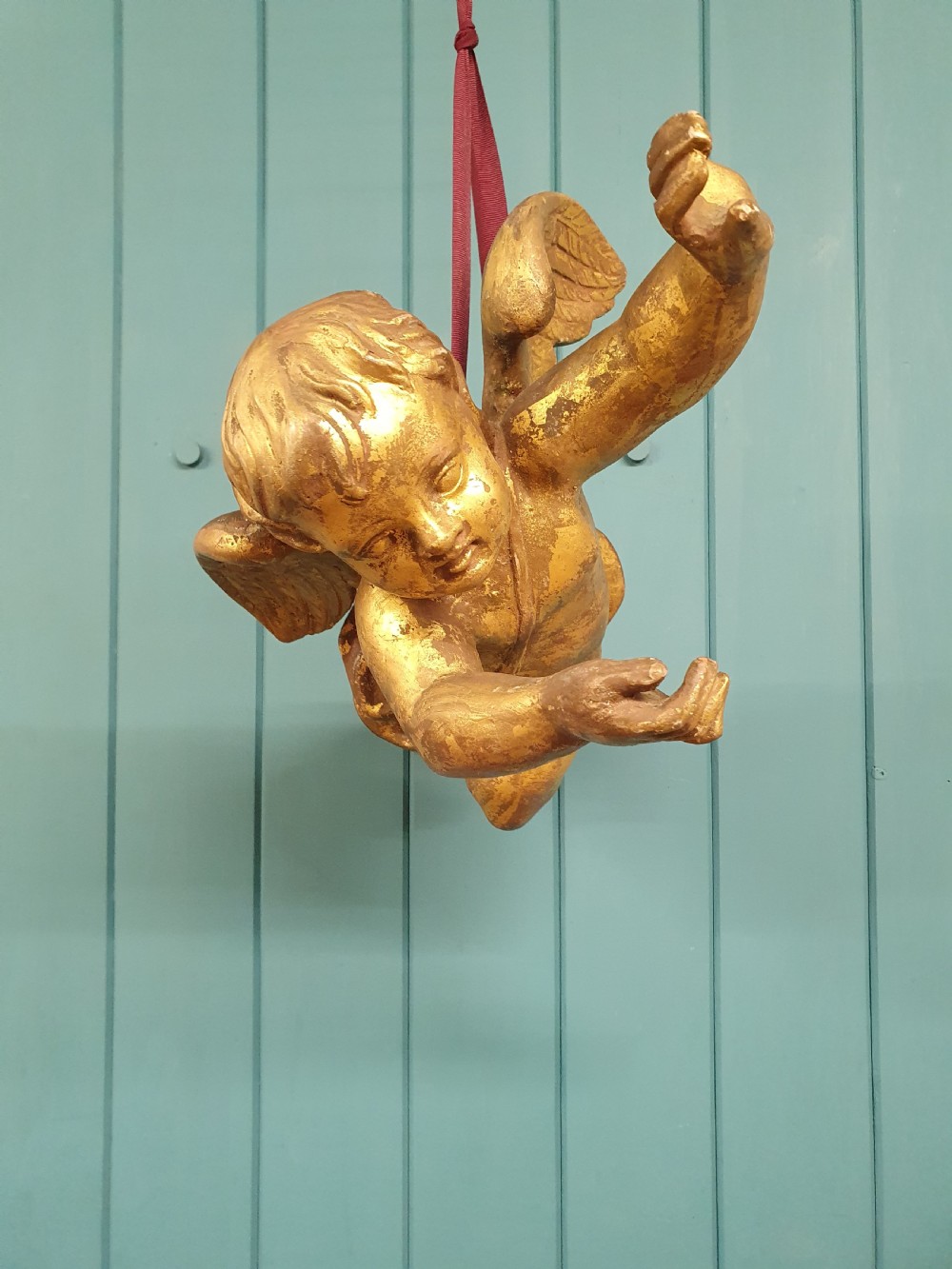 A late 19th-century hand-carved wooden cherub figure with feathered wings and extended limbs, finished in gold leaf gilding. View VI