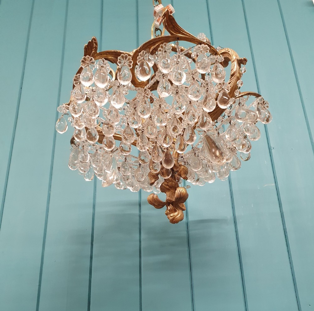 An early 20th-century gilded brass chandelier featuring sweeping leaf-form arms and cascading clear glass teardrop and grape-form droplets. View III
