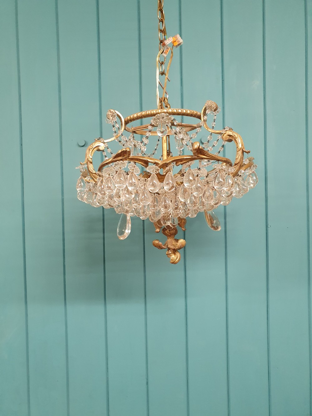 An early 20th-century gilded brass chandelier featuring sweeping leaf-form arms and cascading clear glass teardrop and grape-form droplets. View VIII