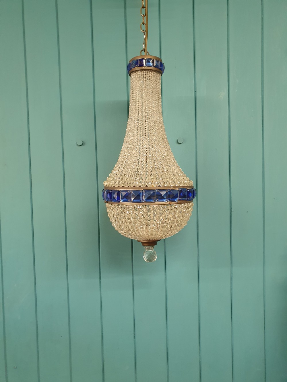 An early 20th-century beaded crystal basket chandelier featuring decorative bands of square-cut cobalt blue glass prisms and a brass frame.