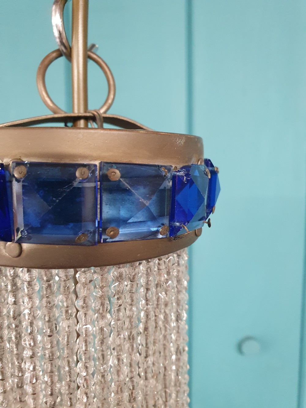 An early 20th-century beaded crystal basket chandelier featuring decorative bands of square-cut cobalt blue glass prisms and a brass frame. View II