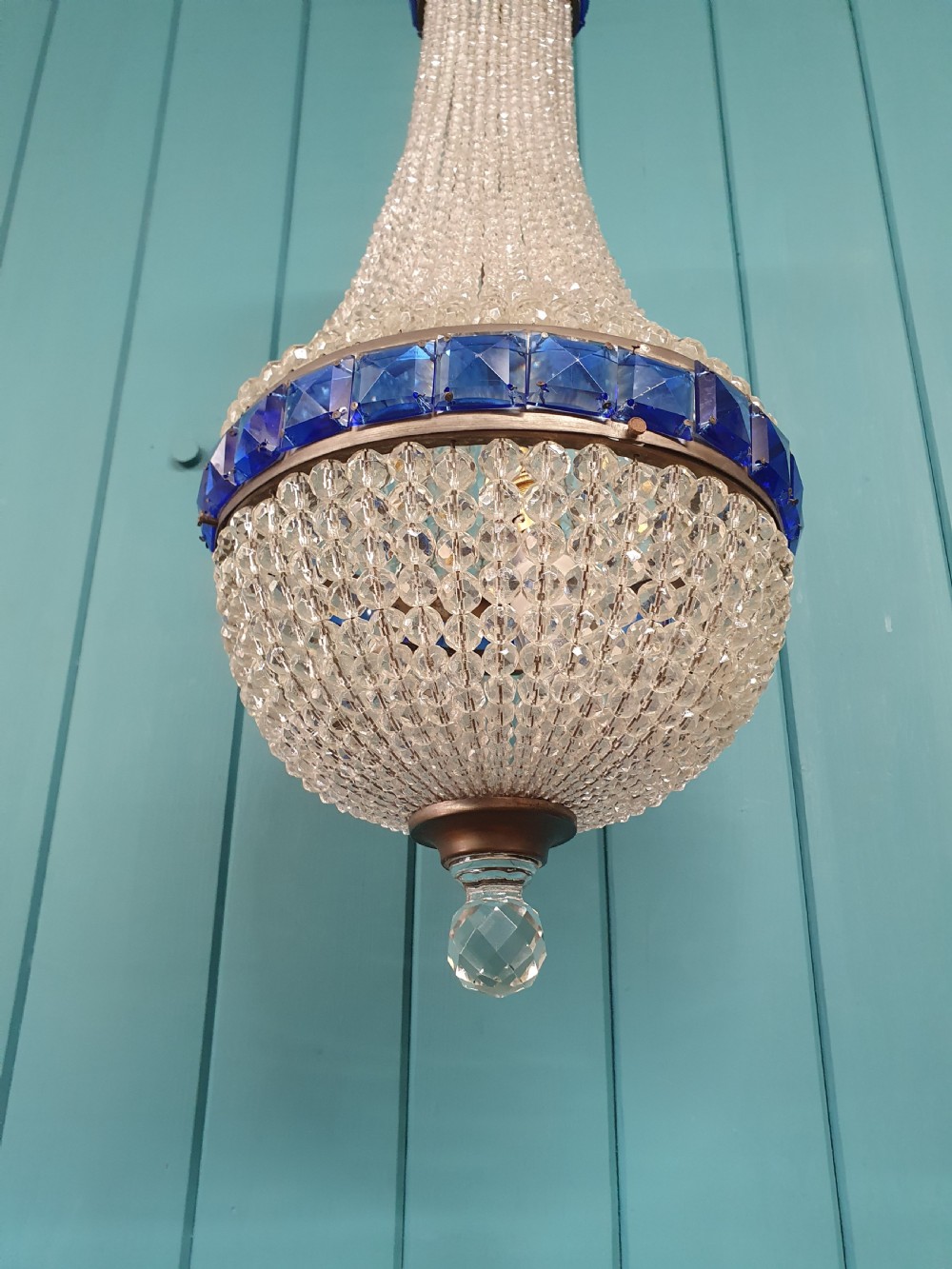 An early 20th-century beaded crystal basket chandelier featuring decorative bands of square-cut cobalt blue glass prisms and a brass frame. View VII