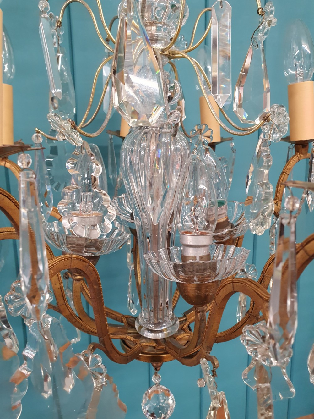 An early twentieth-century French eight-arm glass crystal chandelier featuring a central baluster stem, scrolling metal arms, and suspended cut glass drops. View II