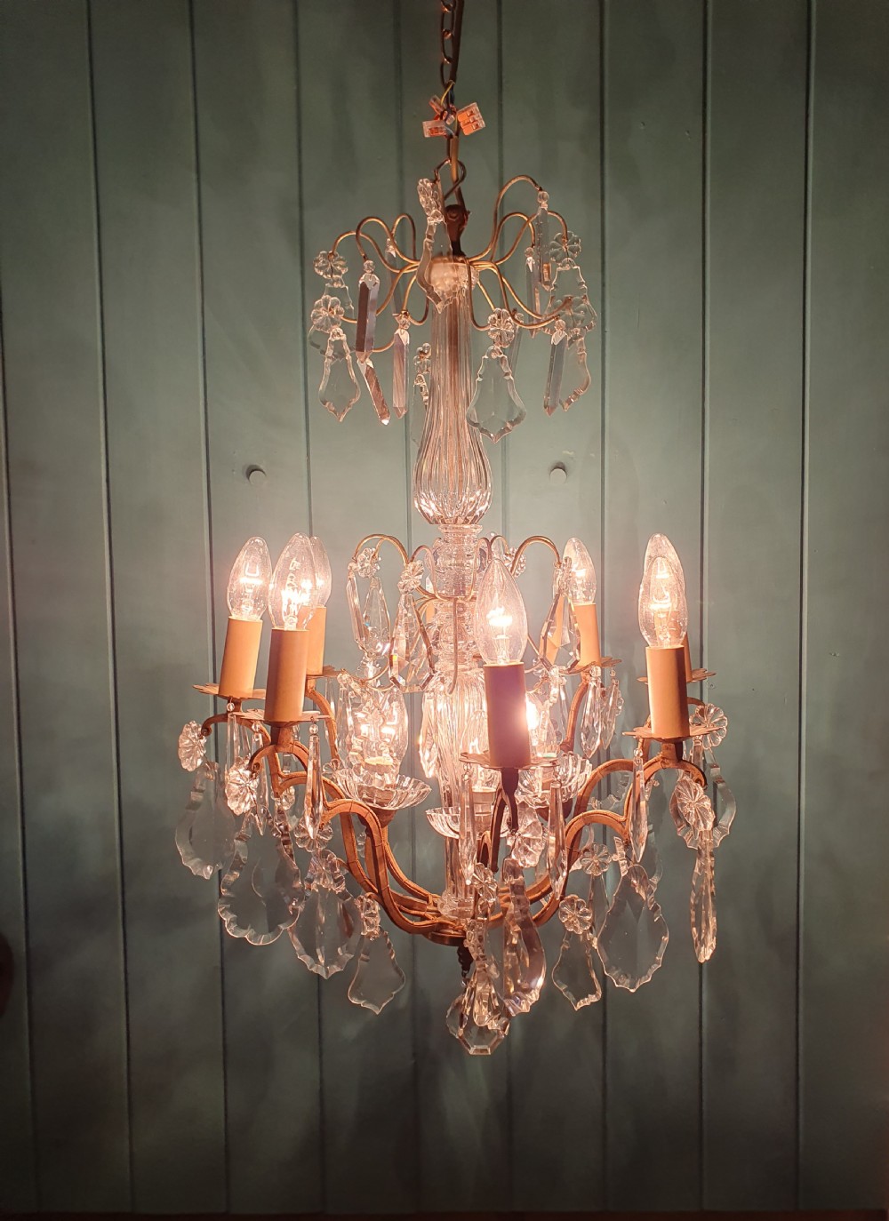 An early twentieth-century French eight-arm glass crystal chandelier featuring a central baluster stem, scrolling metal arms, and suspended cut glass drops. View III