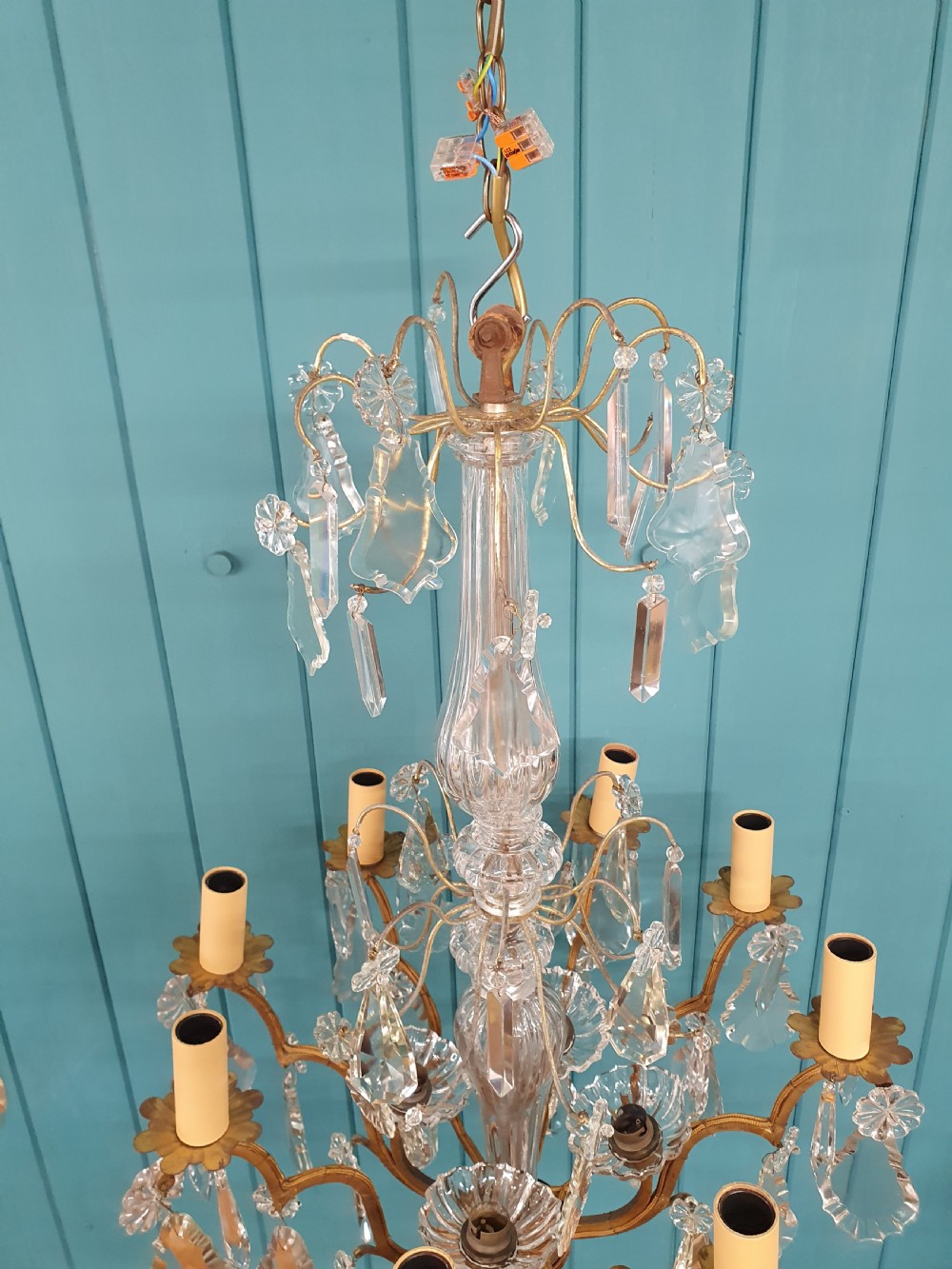An early twentieth-century French eight-arm glass crystal chandelier featuring a central baluster stem, scrolling metal arms, and suspended cut glass drops. View VI