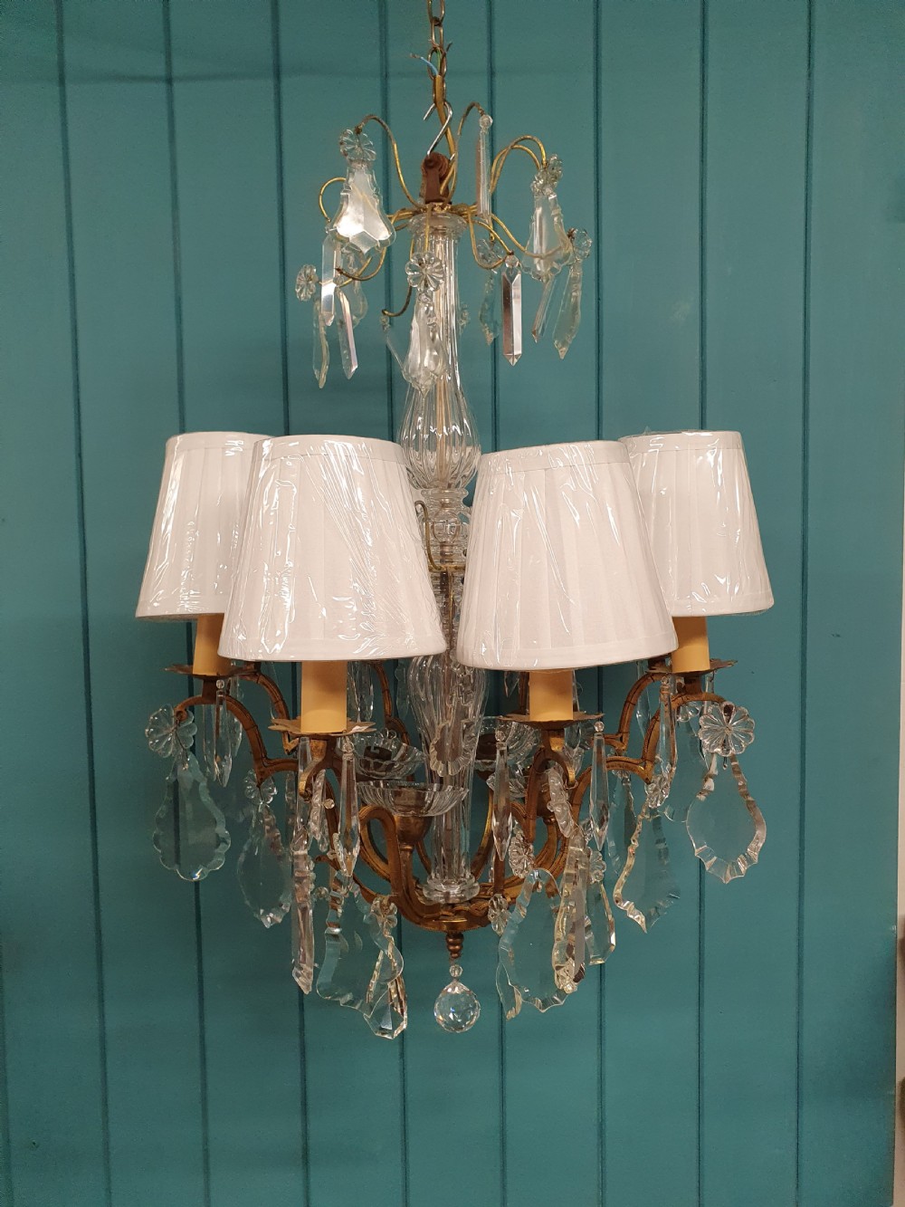 An early twentieth-century French eight-arm glass crystal chandelier featuring a central baluster stem, scrolling metal arms, and suspended cut glass drops. View VII