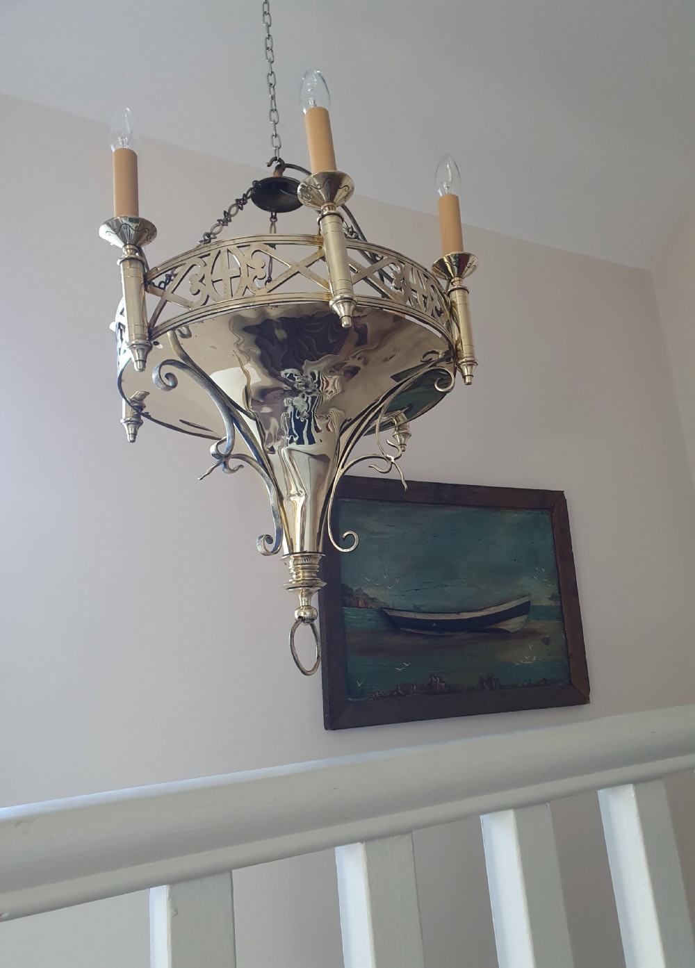 An early twentieth-century Gothic style brass chandelier featuring a pierced geometric gallery, central conical base, and five candle-style bulb holders suspended by chains. View VI