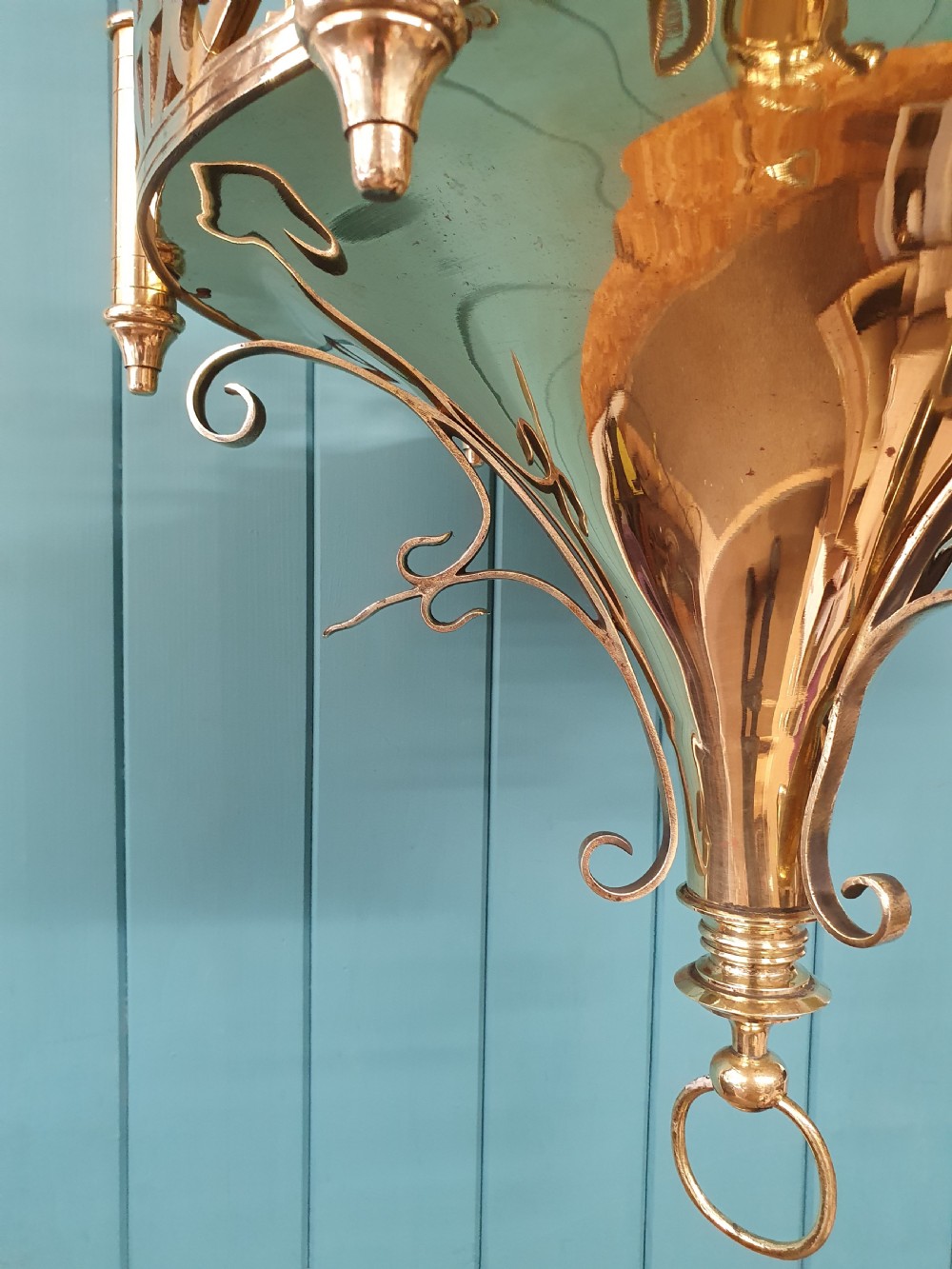 An early twentieth-century Gothic style brass chandelier featuring a pierced geometric gallery, central conical base, and five candle-style bulb holders suspended by chains. View IX