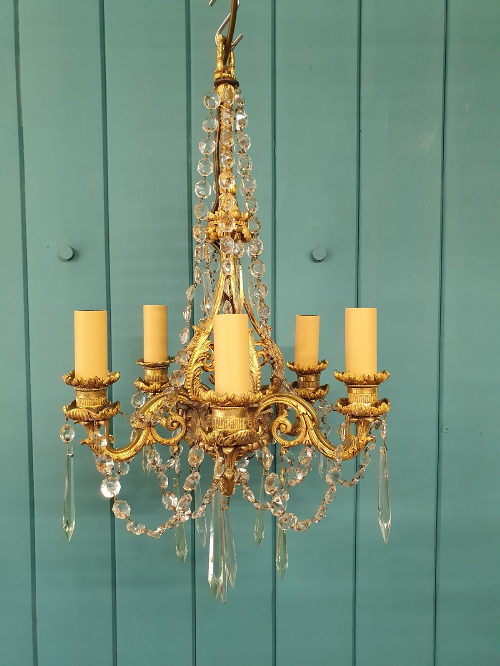 An early 20th-century small gilt brass five-arm chandelier decorated with clear glass crystal swags and teardrop pendants. View II