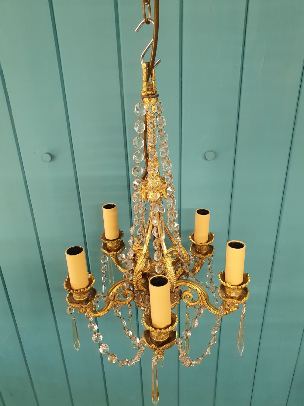 An early 20th-century small gilt brass five-arm chandelier decorated with clear glass crystal swags and teardrop pendants. View VI