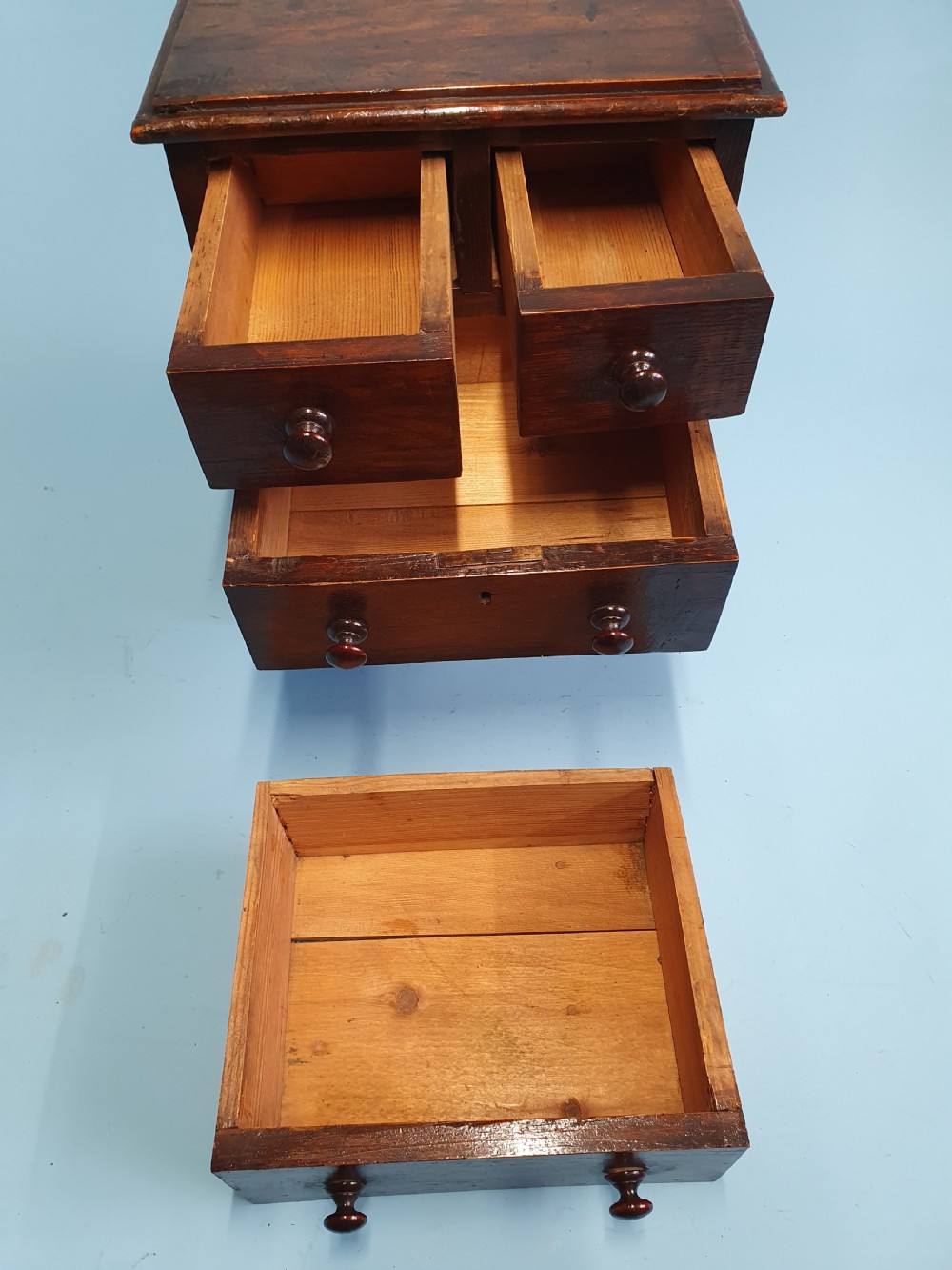 An early nineteenth-century miniature pine chest featuring two short drawers above two long drawers with turned wooden knobs and bun feet. View III