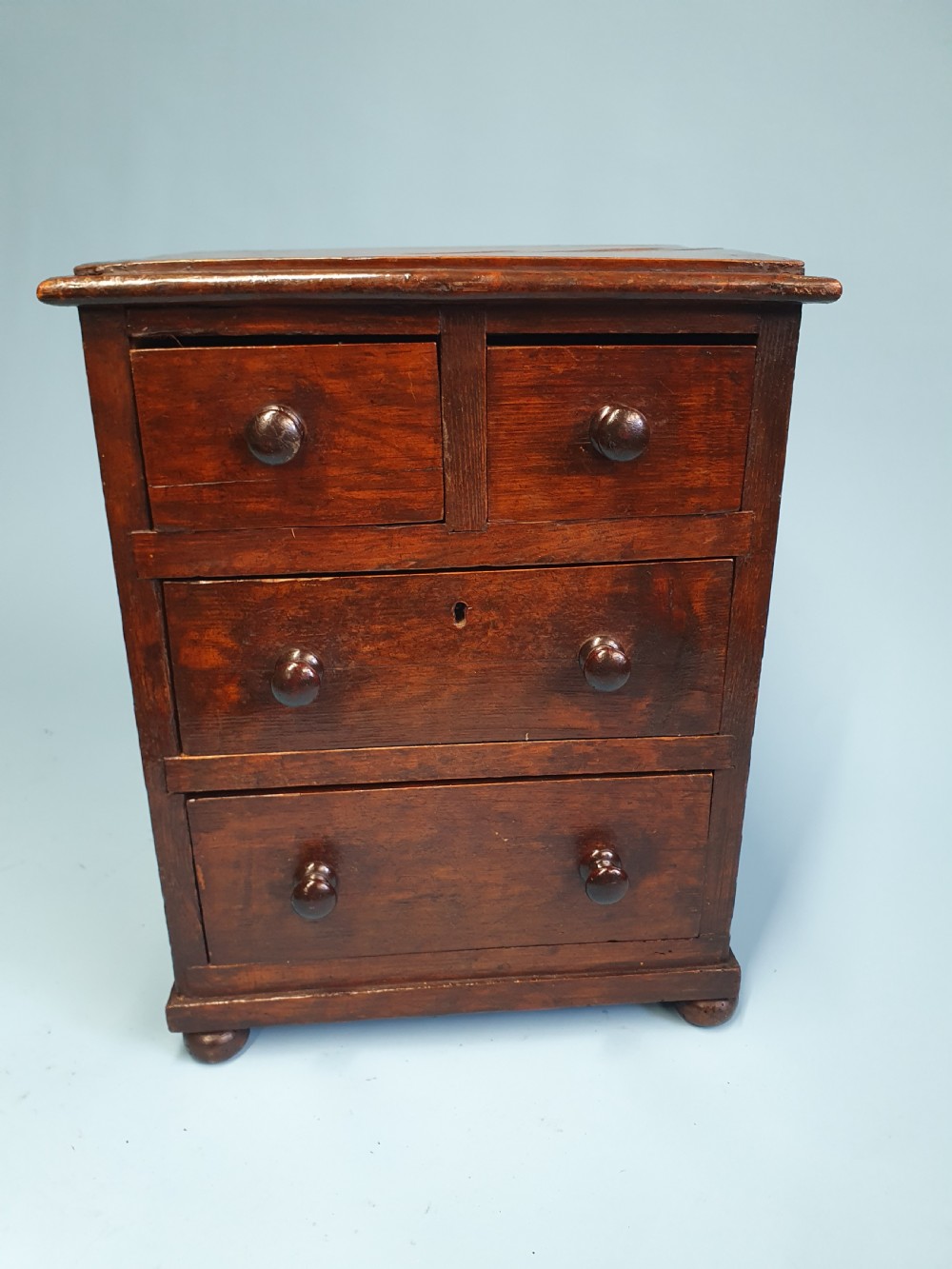 An early nineteenth-century miniature pine chest featuring two short drawers above two long drawers with turned wooden knobs and bun feet. View IV