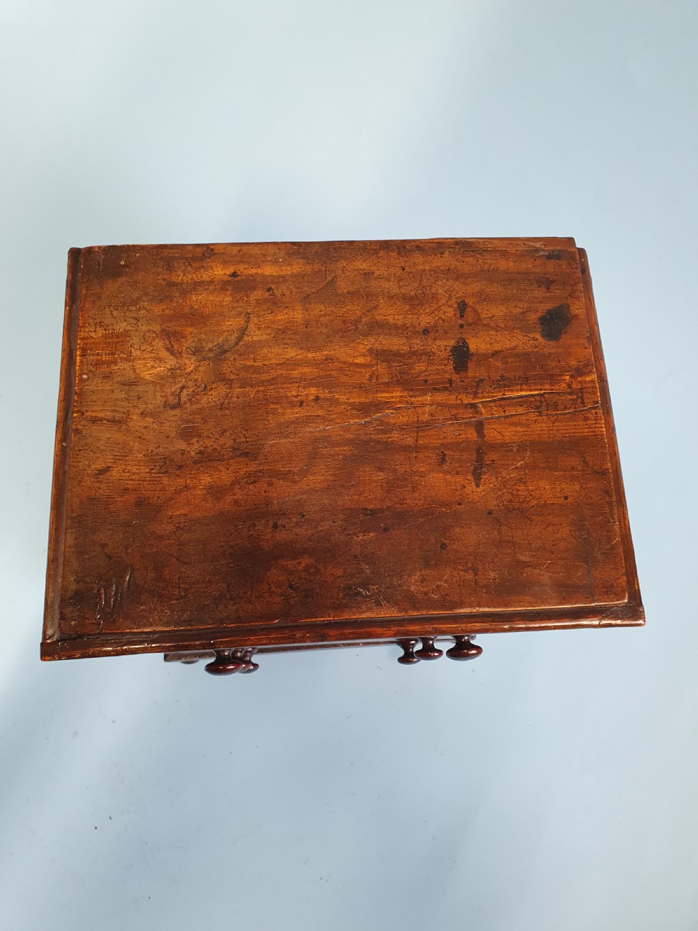 An early nineteenth-century miniature pine chest featuring two short drawers above two long drawers with turned wooden knobs and bun feet. View V