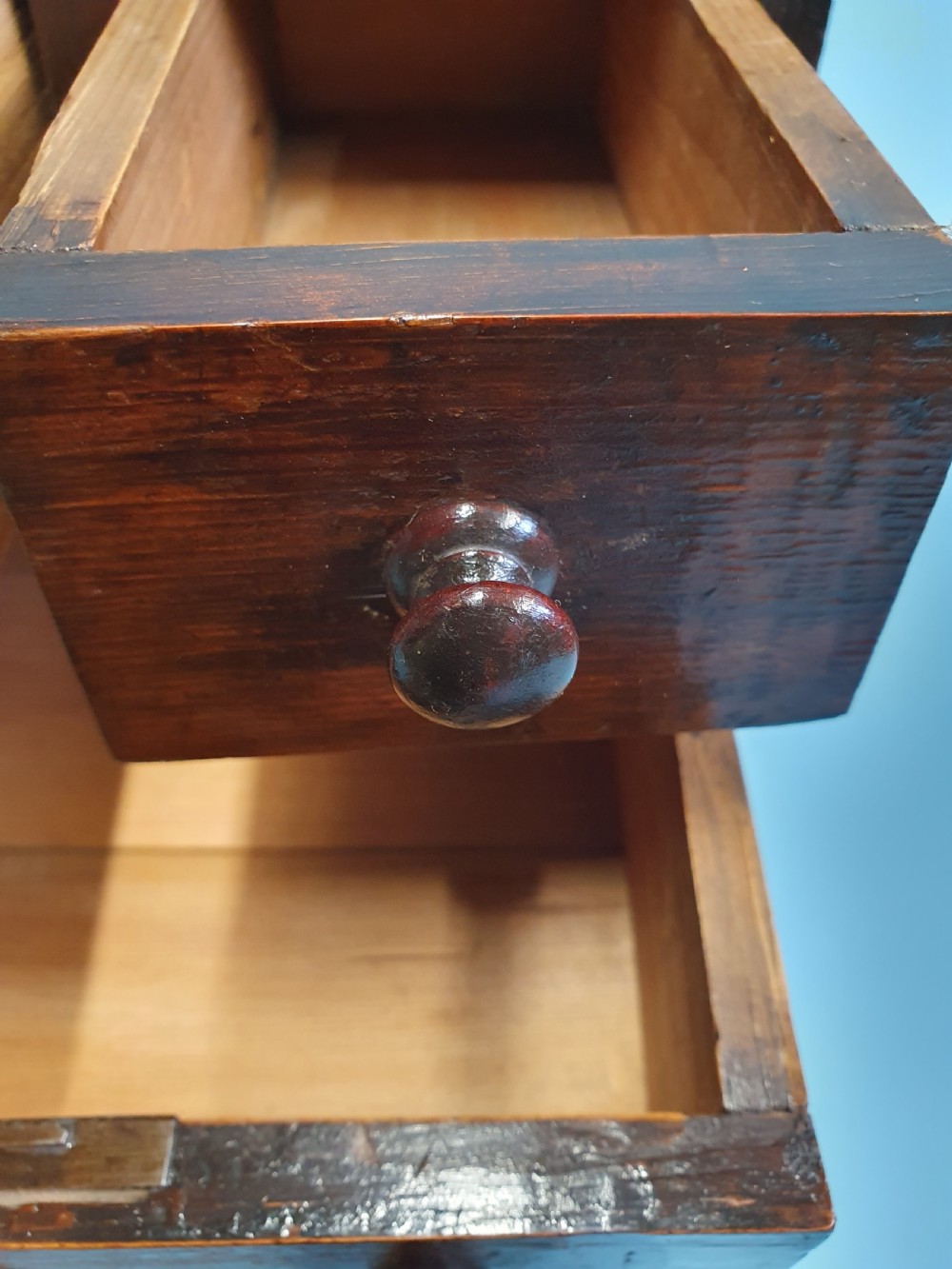 An early nineteenth-century miniature pine chest featuring two short drawers above two long drawers with turned wooden knobs and bun feet. View VI