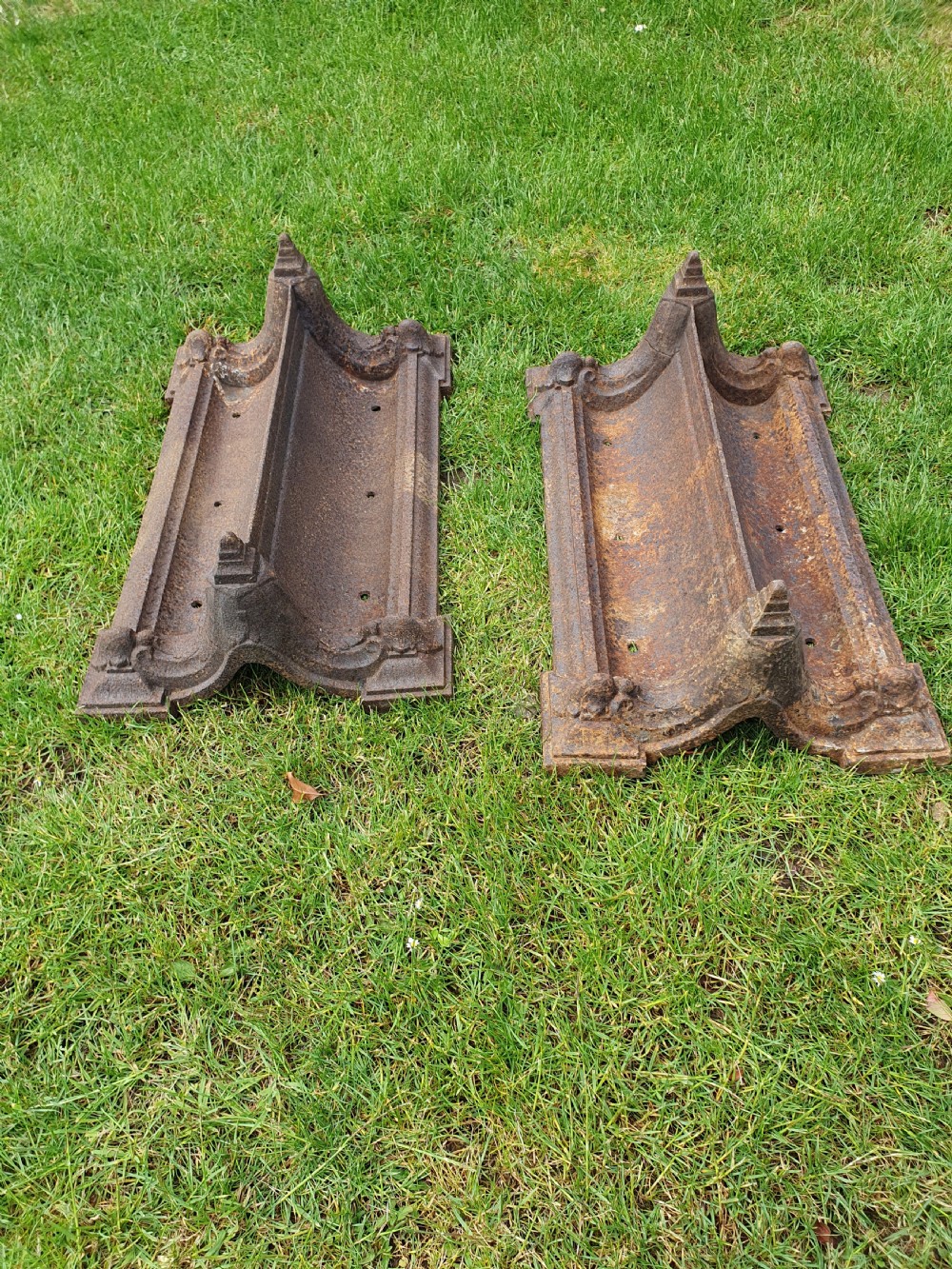 A pair of 19th-century cast iron boot scrapers with moulded trough bases and raised end finials showing natural surface oxidisation.