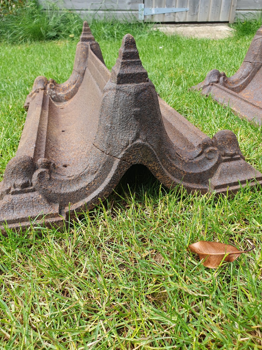 A pair of 19th-century cast iron boot scrapers with moulded trough bases and raised end finials showing natural surface oxidisation. View II