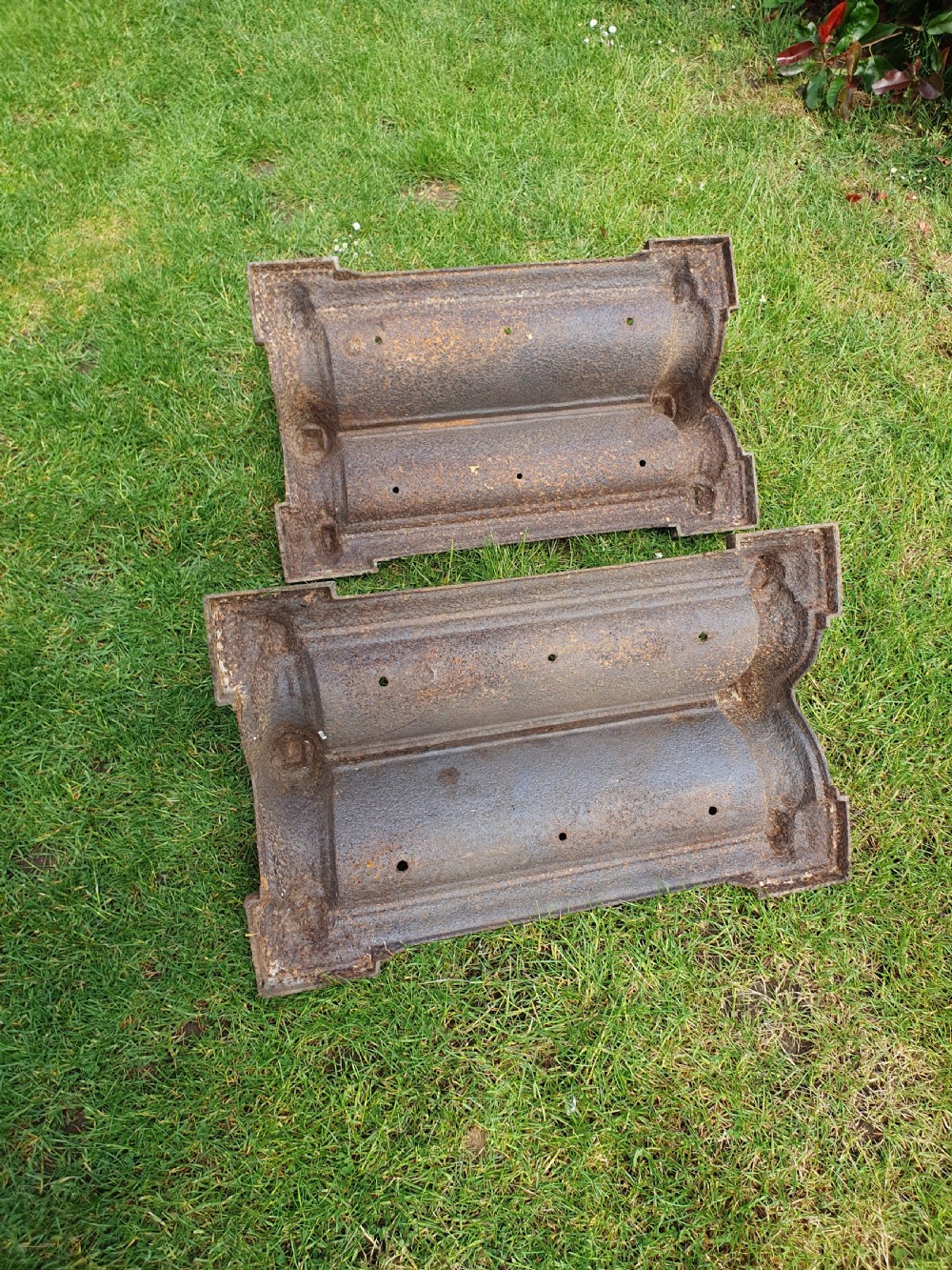 A pair of 19th-century cast iron boot scrapers with moulded trough bases and raised end finials showing natural surface oxidisation. View V