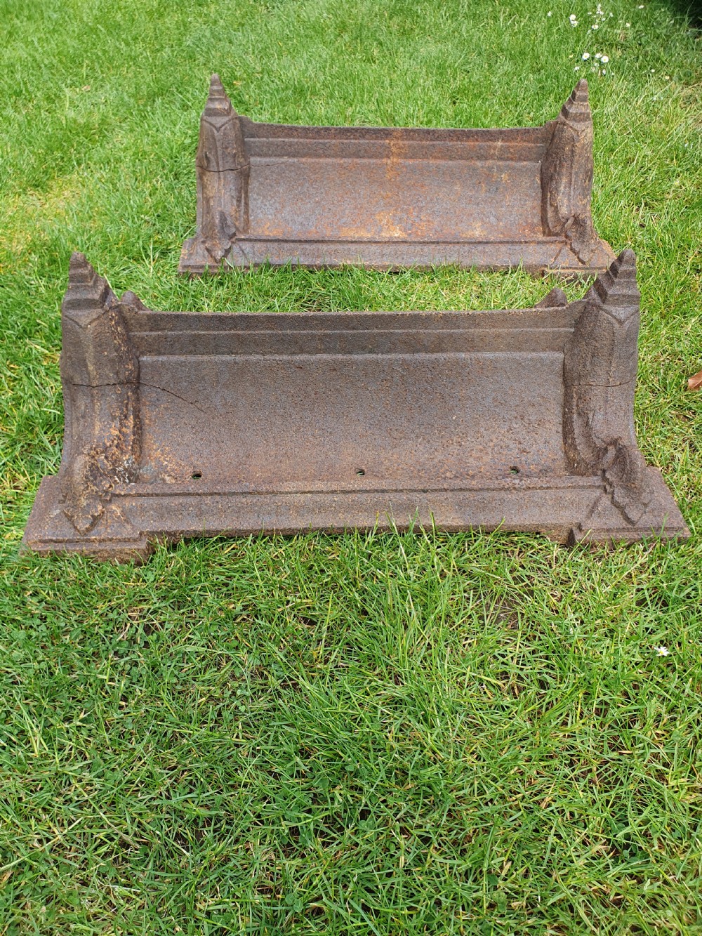 A pair of 19th-century cast iron boot scrapers with moulded trough bases and raised end finials showing natural surface oxidisation. View VI