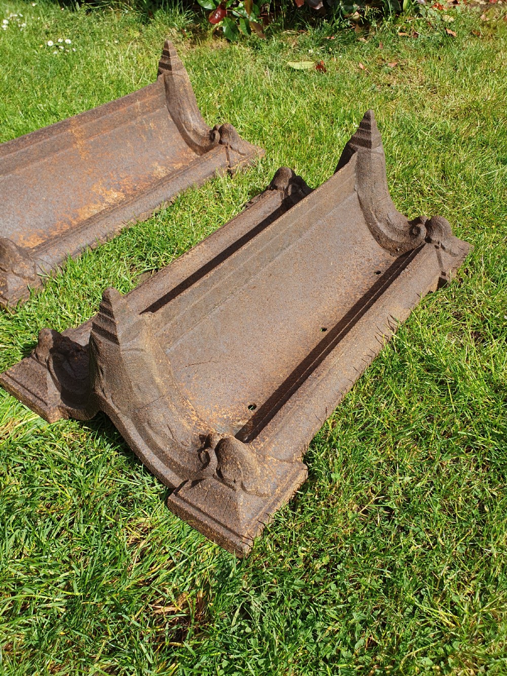 A pair of 19th-century cast iron boot scrapers with moulded trough bases and raised end finials showing natural surface oxidisation. View VII