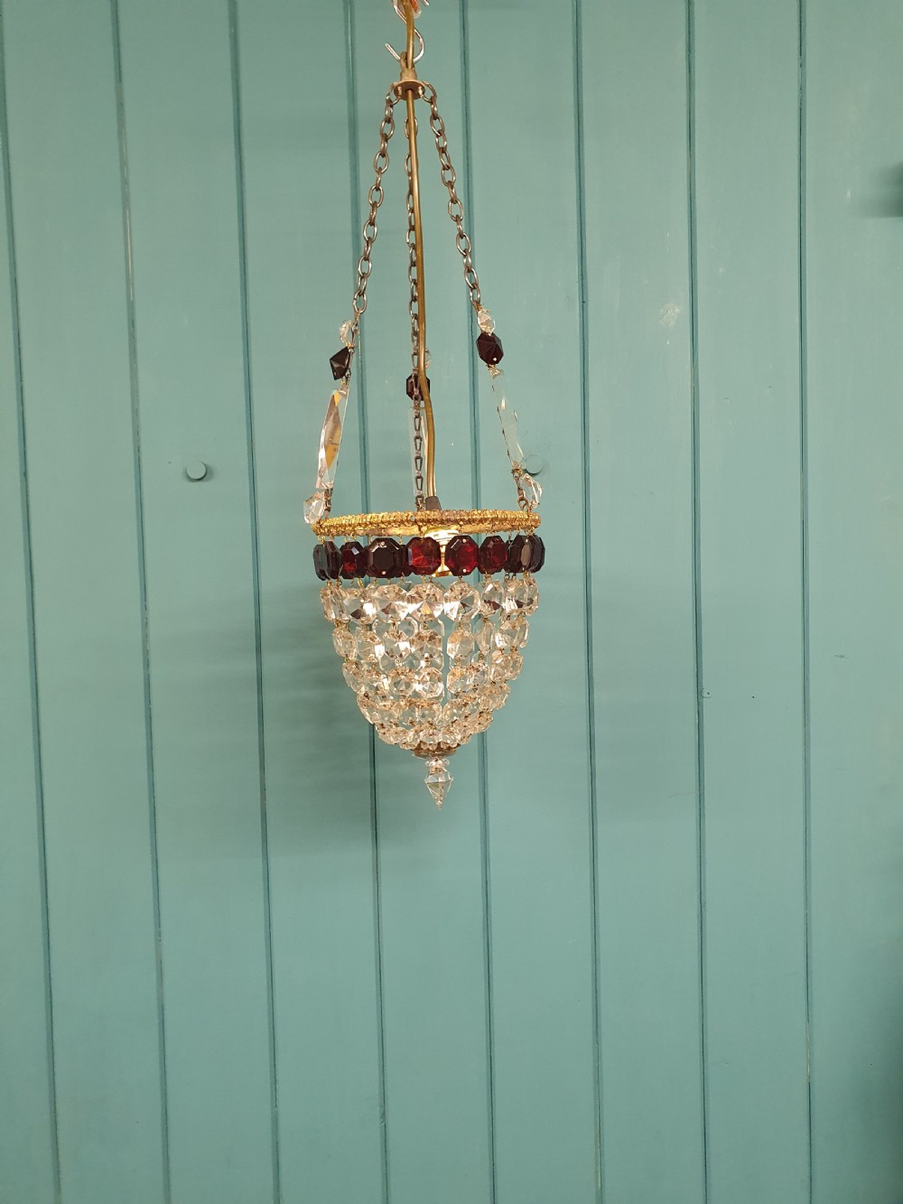 An early 20th-century cut glass basket chandelier suspended by chains, featuring a band of ruby red faceted glass accents above a tapered bead basket structure.