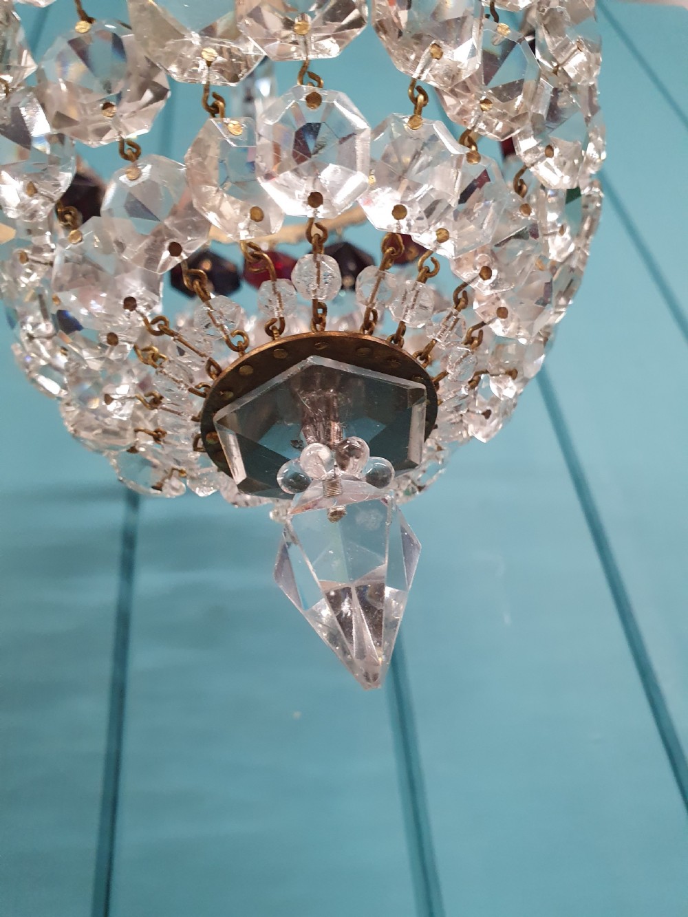 An early 20th-century cut glass basket chandelier suspended by chains, featuring a band of ruby red faceted glass accents above a tapered bead basket structure. View II