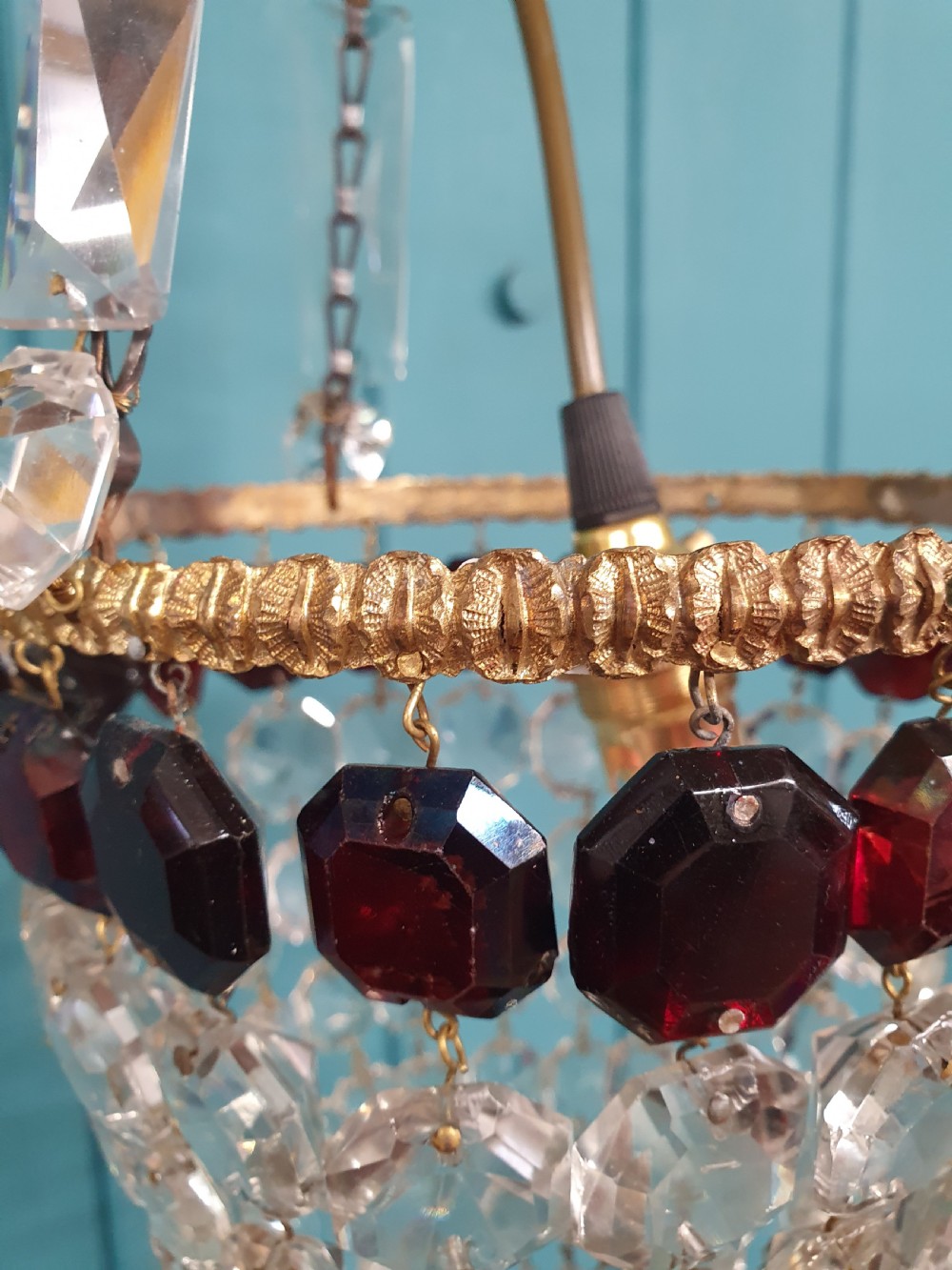 An early 20th-century cut glass basket chandelier suspended by chains, featuring a band of ruby red faceted glass accents above a tapered bead basket structure. View V