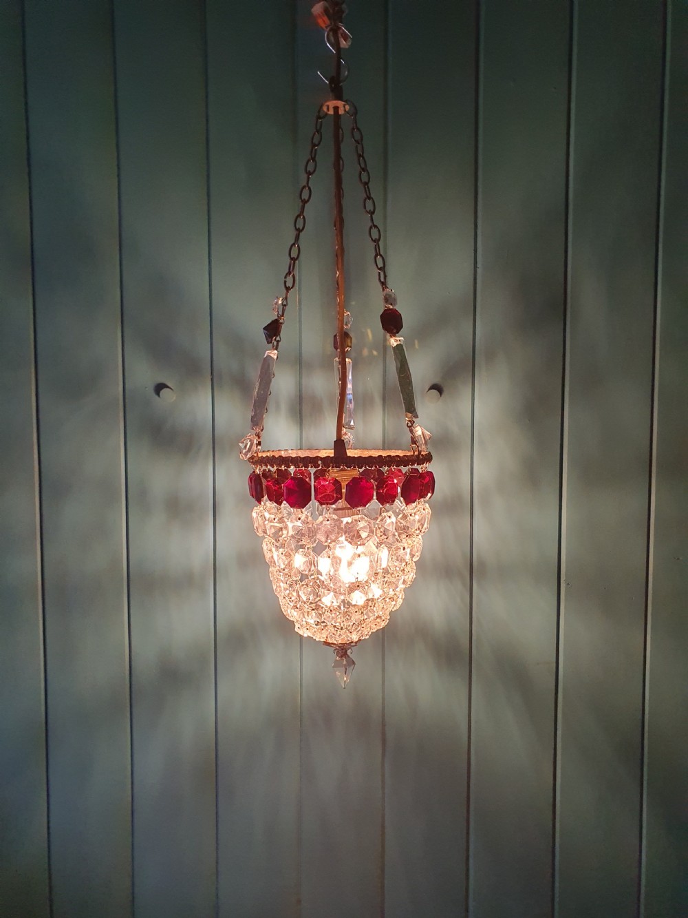 An early 20th-century cut glass basket chandelier suspended by chains, featuring a band of ruby red faceted glass accents above a tapered bead basket structure. View VIII