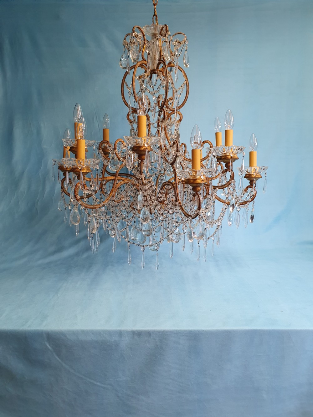 A twelve-arm gilt metal chandelier featuring cut glass crystal drops and beaded swags. View II