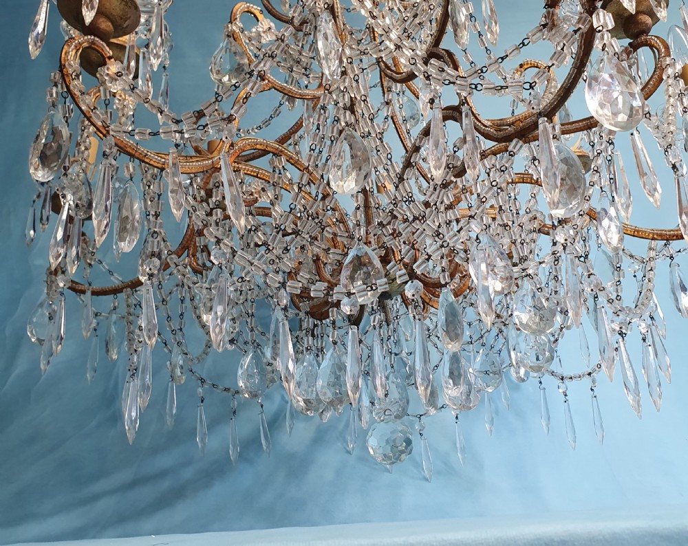 A twelve-arm gilt metal chandelier featuring cut glass crystal drops and beaded swags. View III